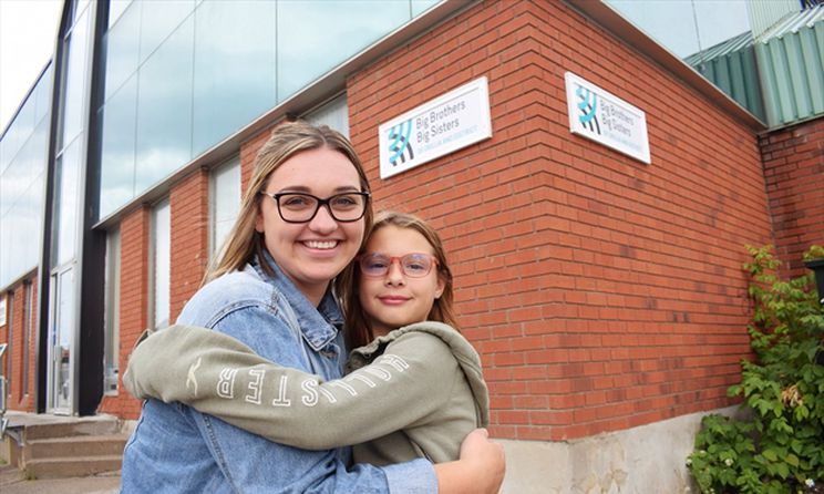 Lauren Oke and Mia Burnside share a hug as Big Sister & Littler Sister out front of Big Brothers Big Sisters of Orillia & District